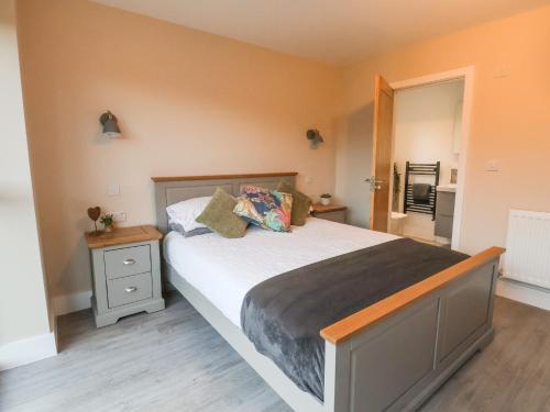 a bedroom with a large bed with a nightstand and a window at Fron Haul - Gwennol in Ruthin