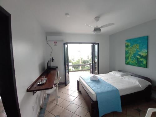a bedroom with a bed and a desk and a window at Pousada Caminho do Mar in Bombinhas