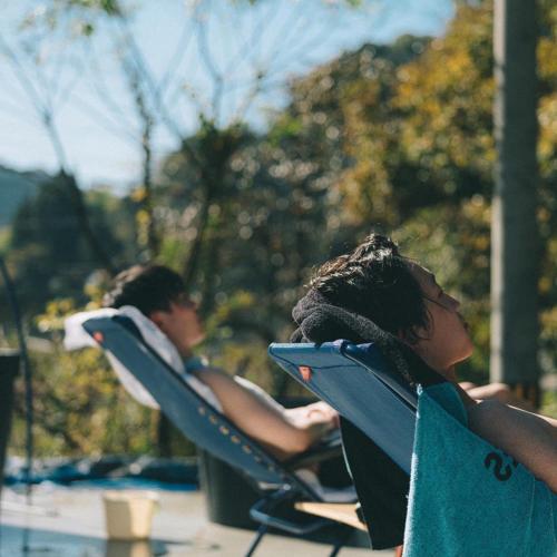 two people sitting in lawn chairs at a pool at Nipponia 甲佐 疏水の郷 in Kosa