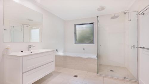 a white bathroom with a sink and a shower at 35 Moreton Parade Kings Beach QLD in Caloundra
