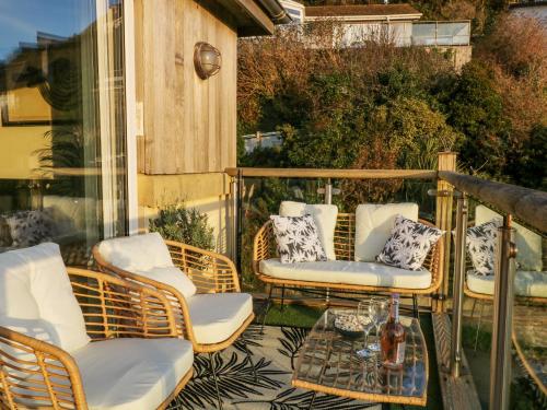 a balcony with wicker chairs and a glass table at A Stone's Throw in Torpoint