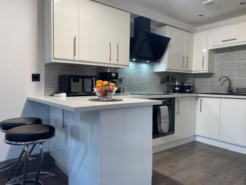 a kitchen with white cabinets and a bowl of fruit on a counter at Modern Spacious 1 Bed Apartment with Free Parking in Trendy Inner London Suburb 15 mins walk to Victoria Line Underground then 20 mins to Oxford Street "West End of London" or 10 mins walk to Overground and 10 mins to London Liverpool St "City of London" in London
