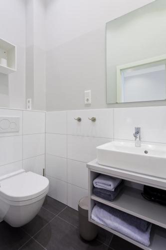 a white bathroom with a toilet and a sink at Soltausche Buchdruckerei - Whg 02 in Norderney