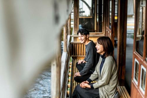 a man and a woman sitting on a train at Nipponia 甲佐 疏水の郷 in Kosa
