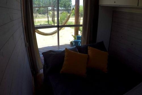 a couch with two pillows in front of a window at Glass in Punta Del Diablo