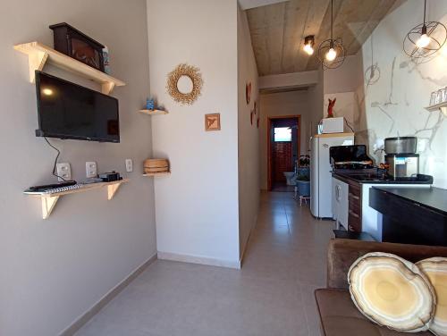 a living room with a kitchen with a tv on the wall at D'Santos Hospedaria. Aconchego perto de Tiradentes in Coroas