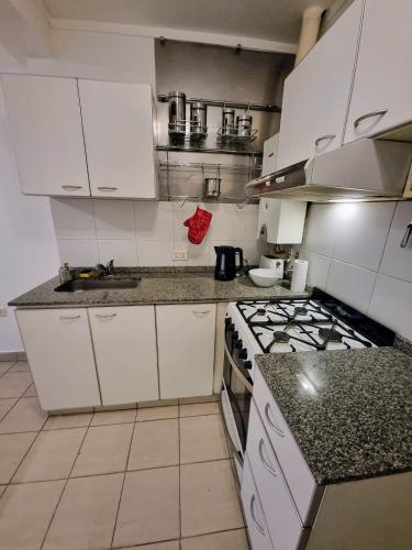 a kitchen with white cabinets and a stove top oven at Paraná Confort in Paraná