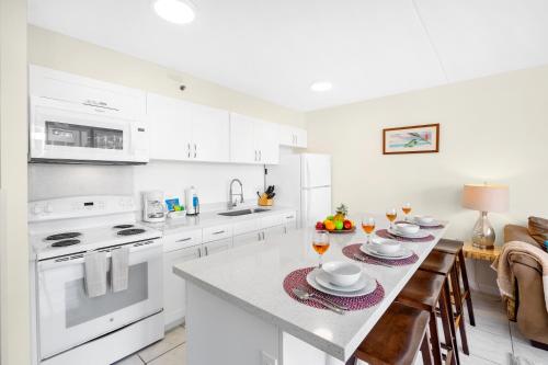 a kitchen with white appliances and a table with glasses of wine at 7FL Waikiki Retreat with Parking, Walk to Beach in Honolulu