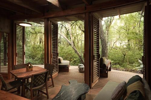 a screened in porch of a cabin with a table and chairs at Zunya in Santa Teresa Beach