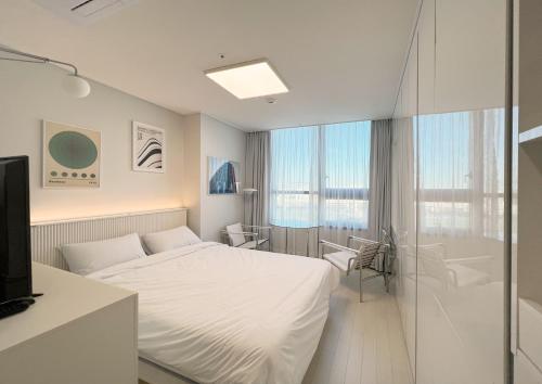a white bedroom with a bed and a shower at UH FLAT THE SONGDO in Incheon