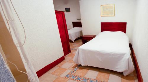 a small bedroom with a white bed and a red door at Hotel Nueva Antequera in Oaxaca City