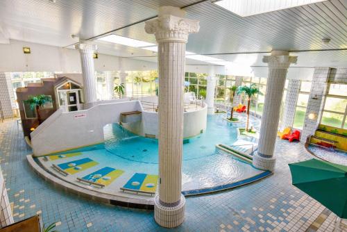 una gran piscina cubierta con un tobogán en un edificio en Hotel Aso No Tsukasa en Aso
