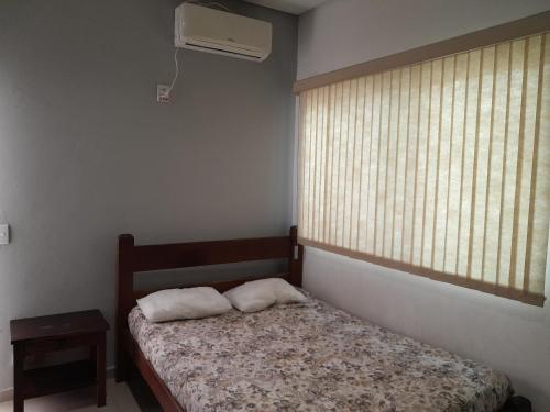 een slaapkamer met een bed en een raam met een ventilator bij Sunny Chalés na prainha do jacaré muito próximo in Caraguatatuba