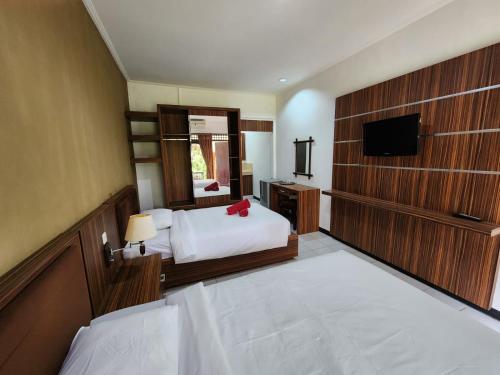 a hotel room with a bed and a television at Ramayana Hotel in Sanur