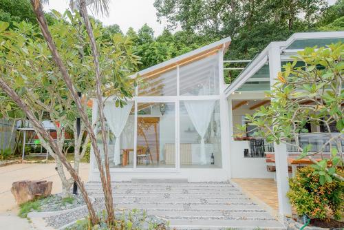 a house with white walls and windows and trees at Seashell Village Resort in Chao Lao Beach