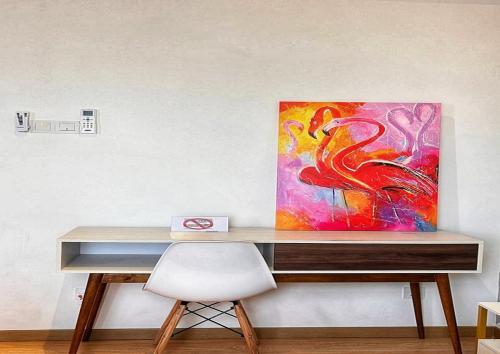 a desk with a painting on the wall with a chair at Comfy Imperium Residence Kuantan Studio Seaview in Kuantan