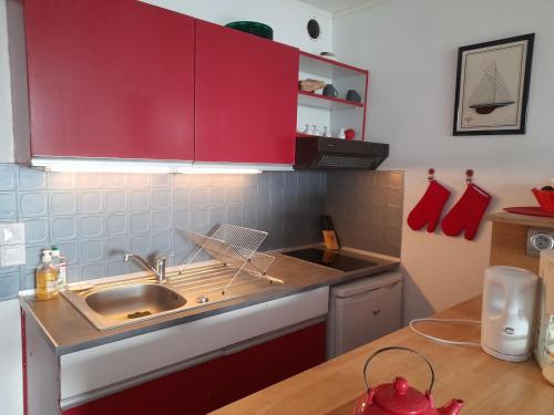 - une cuisine avec des placards rouges et un évier dans l'établissement Appartement Arcachon, 1 pièce, 4 personnes - FR-1-319-93, à Arcachon