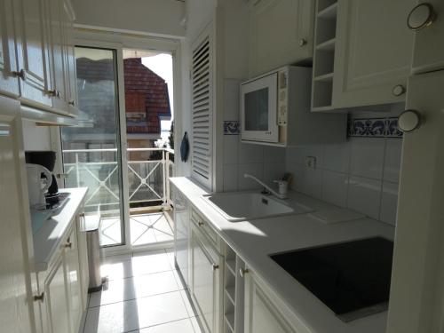 une cuisine blanche avec un évier et une fenêtre dans l'établissement Appartement T3 en bord de mer avec balcon, WIFI et parking sécurisé - FR-1-374-23, à Arcachon
