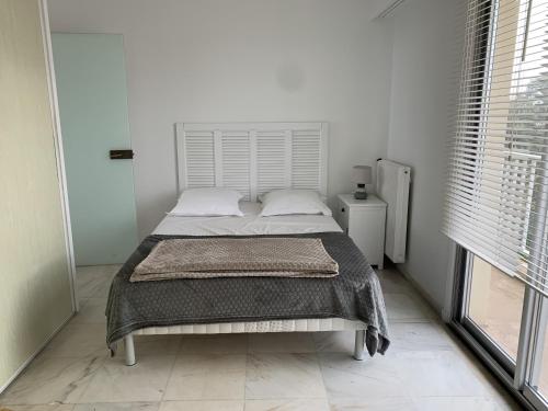 Ce lit se trouve dans un dortoir blanc doté d'une grande fenêtre. dans l'établissement Appartement T3 Centre Arcachon, Vue Bassin, Parking, Animaux OK, Wifi - FR-1-374-74, à Arcachon