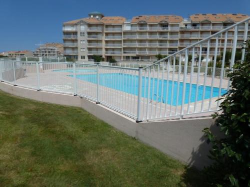 une clôture autour d'une piscine avec un bâtiment dans l'établissement Studio avec Piscine, Parking et Balcon aux Sables-d'Olonne - FR-1-197-380, à Les Sables-dʼOlonne