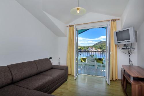 uma sala de estar com um sofá e uma porta de vidro deslizante em Apartment and Rooms Nikola em Zastražišće