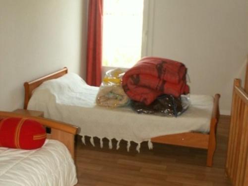 - une chambre avec 2 lits et un sac à dos rouge sur le lit dans l'établissement Maison Vendéenne avec Piscine Proche de la Plage et Commerces, Animaux Acceptés sur Demande - FR-1-476-28, à La Faute-sur-Mer