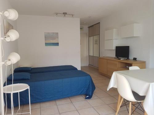 - une chambre avec un lit bleu, une table et des chaises dans l'établissement Studio clim. proche plage, commerces & gare avec WiFi, parking en option - FR-1-466A-15, à Saint-Raphaël