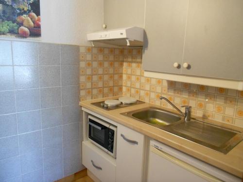 une cuisine avec un évier et un micro-ondes dans l'établissement Charmante Maisonnette à 200m de la Plage avec Jardin et Parking Privé - FR-1-476-9, à La Faute-sur-Mer
