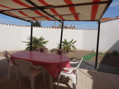 - une table et des chaises sous un parasol sur la terrasse dans l'établissement Maison confortable, proche plages et centre, 4 pers, terrasse, wifi, centre L'Aiguillon-sur-Mer - FR-1-476-11, à LʼAiguillon-sur-Mer