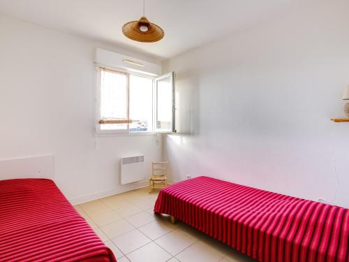 - une chambre avec 2 lits et une couverture rouge dans l'établissement Appartement T3 avec Terrasse - à 50m de la Plage de Biscarrosse, Parking Privé Inclus - FR-1-521-15, à Biscarrosse-Plage