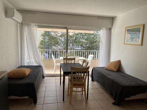 une chambre avec deux lits, une table et une fenêtre dans l'établissement Studio climatisé pour 3 pers, à 50m de la plage, centre-ville Saint-Raphaël, WiFi, parking dispo - FR-1-466A-38, à Saint-Raphaël