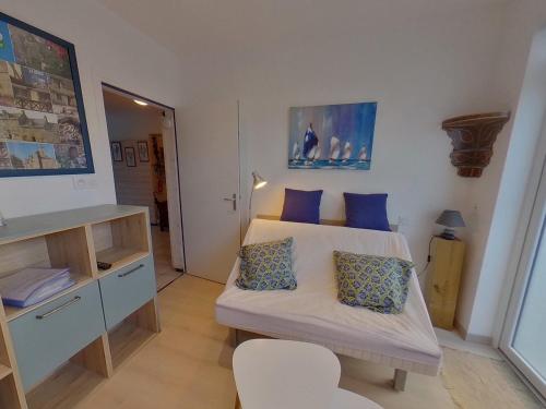 Cette petite chambre comprend un lit avec des oreillers bleus. dans l'établissement Studio rénové à Port-Louis, proche plage et centre, jardin commun, 2 couchages, WiFi inclus - FR-1-349-143, à Port-Louis