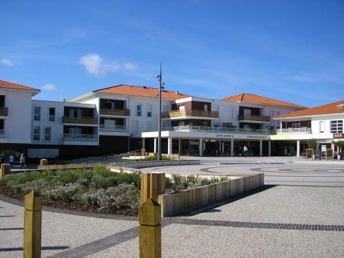 un groupe de bâtiments avec une clôture dans une cour dans l'établissement Appartement T3 moderne à Biscarrosse Plage, proche océan, terrasse et parking - FR-1-521-9, à Biscarrosse-Plage