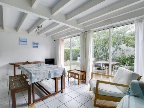 un salon avec une table, des chaises et des fenêtres dans l'établissement Maison 4 pers. avec jardin clos, proche plage et centre, quartier calme - FR-1-521-24, à Biscarrosse-Plage