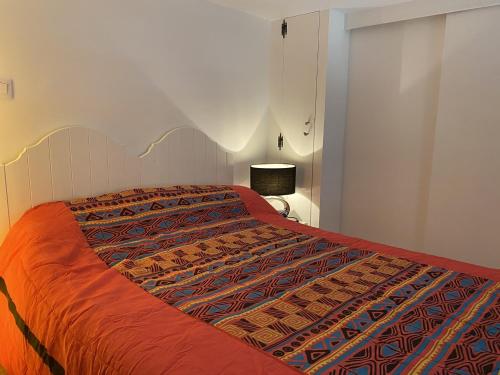 - un lit avec une couette en orange dans une chambre dans l'établissement Cabourg: Appartement 3P à 200m de la plage, 2 chambres, balcon, internet - FR-1-487-277, à Cabourg