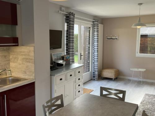 une cuisine avec un évier et une table avec des chaises dans l'établissement Charmant cottage familial près de la thalasso, jardin privatif, parking, Wi-Fi, 6 pers. - FR-1-487-276, à Cabourg