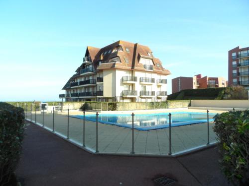 un immeuble avec une piscine devant un immeuble dans l'établissement Cabourg: Appartement 2 pièces proche plage avec piscine et parking - FR-1-487-299, à Cabourg