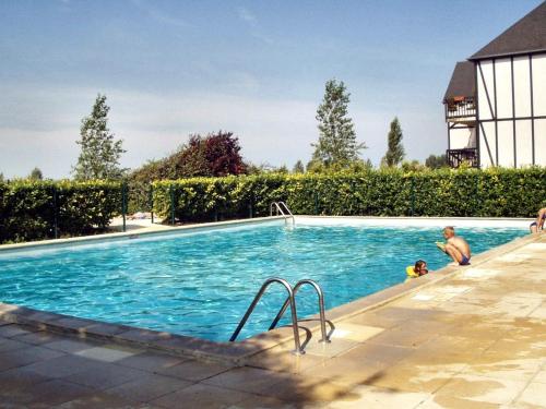 - une piscine avec 2 personnes dans l'eau dans l'établissement Charmant Cottage Normand avec Jardin, Proche Hippodrome, Piscine Chauffée et Tennis, Parking Privé - FR-1-487-288, à Cabourg