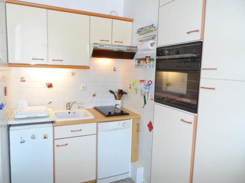 cocina con armarios blancos y nevera blanca en Appartement Cabourg, 2 pièces, 4 personnes - FR-1-487-290, en Cabourg
