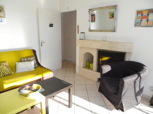 - un salon avec un canapé jaune et une cheminée dans l'établissement Appartement T2 avec Jardin, Proche Centre et Plage de Cabourg, Parking Inclus - FR-1-487-295, à Cabourg