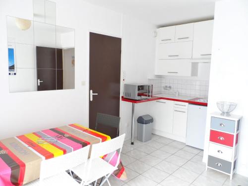 une cuisine avec des armoires blanches et une table dans une pièce dans l'établissement Appartement 2 pièces avec balcon ensoleillé près de l'hippodrome de Cabourg - FR-1-487-297, à Cabourg