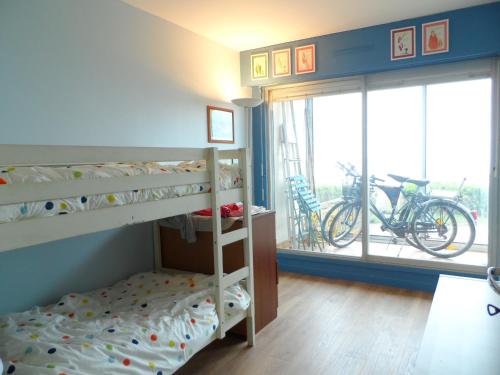 une chambre avec des lits superposés avec un vélo à la fenêtre dans l'établissement Cabourg : Appartement moderne 4/5 pièces, accès plage, 8 pers, jardin et terrasse, parking, WIFI - FR-1-487-304, à Cabourg