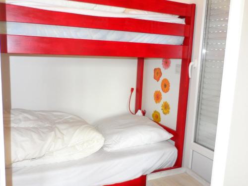 Ce lit superposé rouge et blanc se trouve dans un dortoir. dans l'établissement CABOURG - Appartement 3 pièces proche plage avec piscine et tennis - FR-1-487-303, à Cabourg