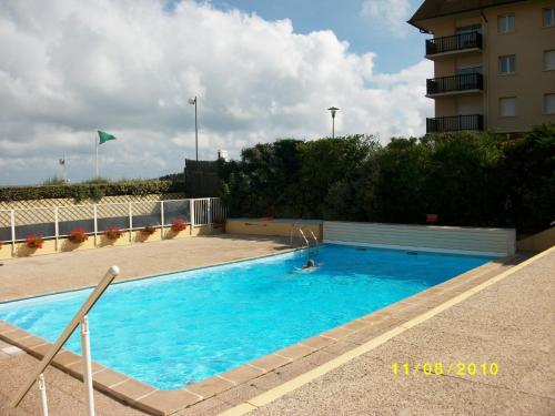 une personne nageant dans une grande piscine bleue dans l'établissement CABOURG - Appartement 3 pièces proche plage avec piscine et tennis - FR-1-487-303, à Cabourg