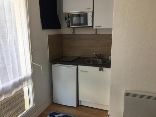 une petite cuisine avec un évier et un micro-ondes dans l'établissement Appartement 2 pièces avec terrasse près de la plage - Merville-Franceville - FR-1-487-311, à Merville-Franceville-Plage