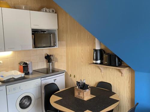 une cuisine avec une machine à laver et une table avec des chaises dans l'établissement Appartement 2 Pièces à Cabourg, Proche Plage et Thalasso, Balcon, Wifi, 4 Pers - FR-1-487-315, à Cabourg
