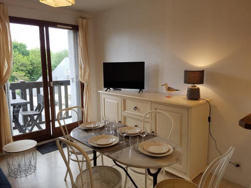 une salle à manger avec une table avec des chaises et une télévision dans l'établissement Charmant T2 à Cabourg, proche plage et centre-ville, balcon et parking gratuit - FR-1-487-312, à Cabourg