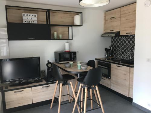 une cuisine avec une table et des chaises ainsi qu'une télévision dans l'établissement Studio Front de Mer avec Terrasse et Accès Direct Plage à Merville-Franceville - FR-1-487-329, à Merville-Franceville-Plage