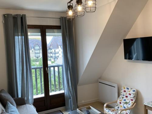 - un salon avec une grande fenêtre et une télévision dans l'établissement Appartement rénové proche plage et thalasso, 2 pièces, balcon, Wifi, TV, équipements bébé - Cabourg - FR-1-487-322, à Cabourg