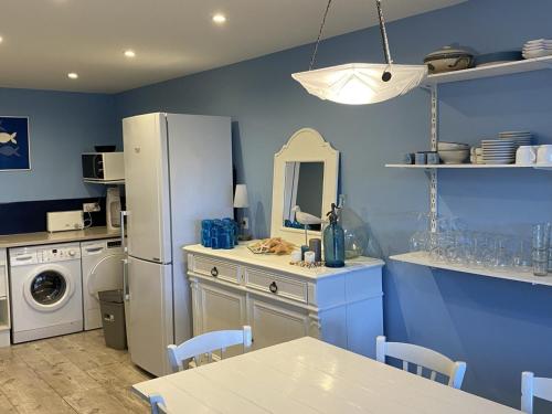 Il comprend une cuisine dotée de murs bleus et d'un réfrigérateur blanc. dans l'établissement Grand Duplex en Front de Mer avec 3 Chambres, Animaux Acceptés, Equipements Complets, Cabourg - FR-1-487-321, à Cabourg